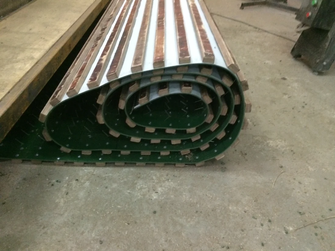 Assembled spiked conveyor belt rolled up in a workshop